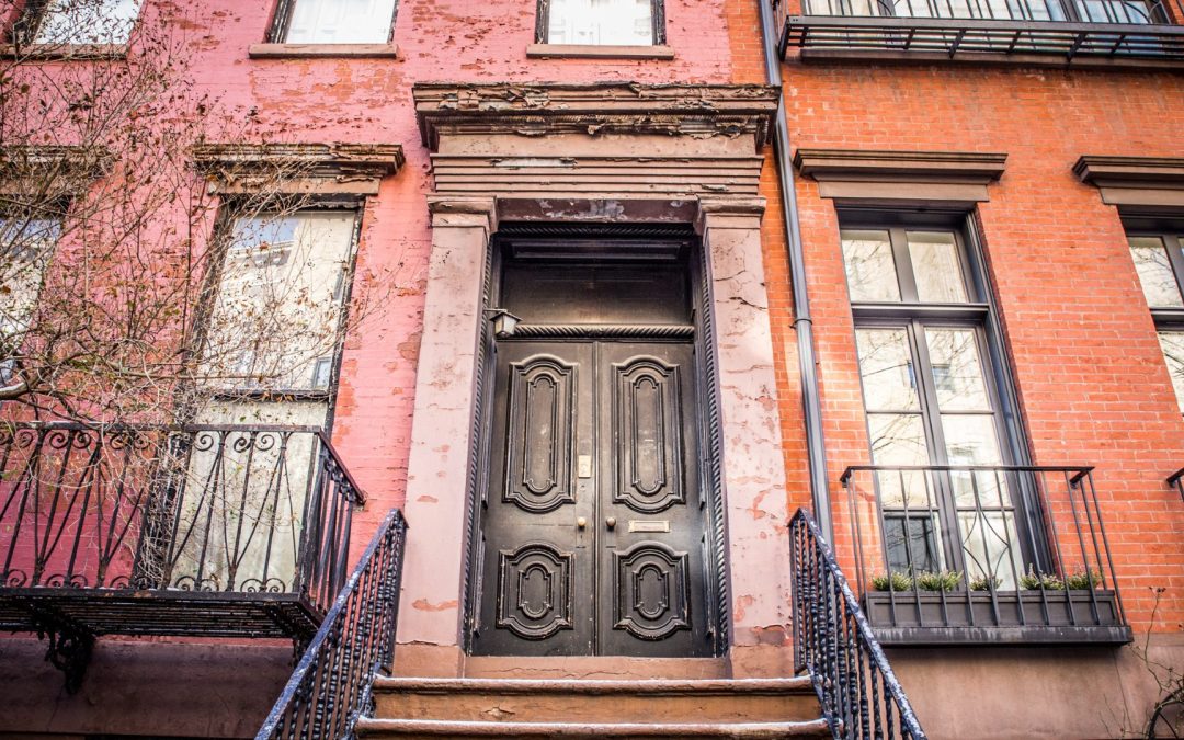 An old, weathered door in front of a New York apartment home.