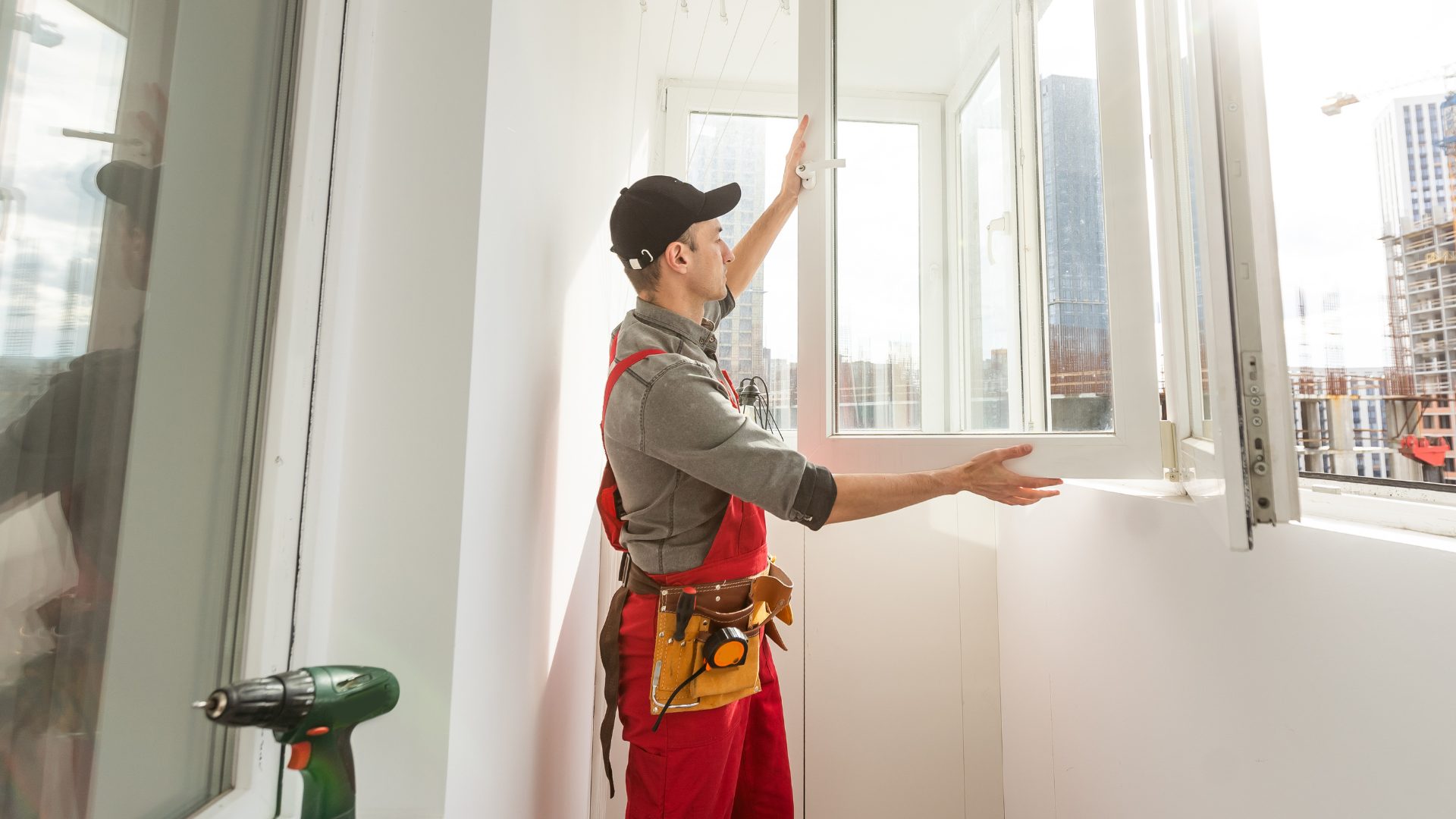 A professional in red coveralls installs a new window in a home.