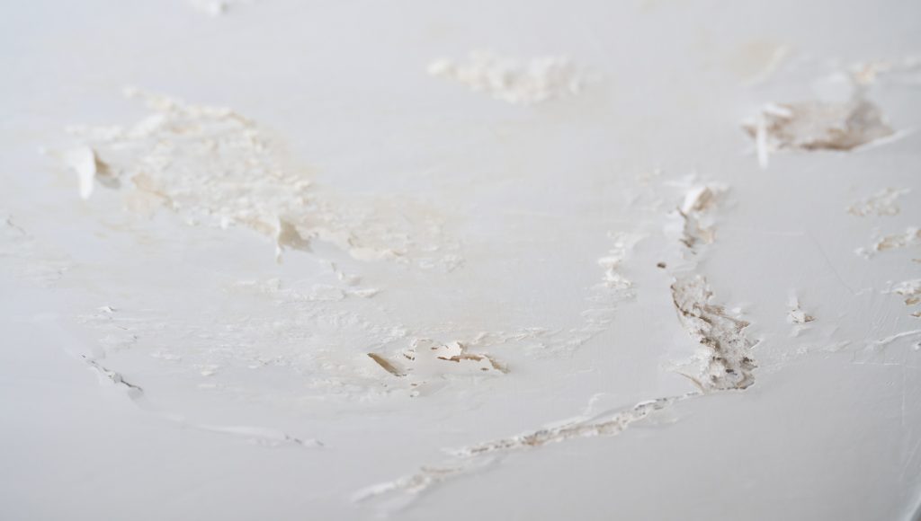 An interior ceiling with obvious water damage and peeling paint.