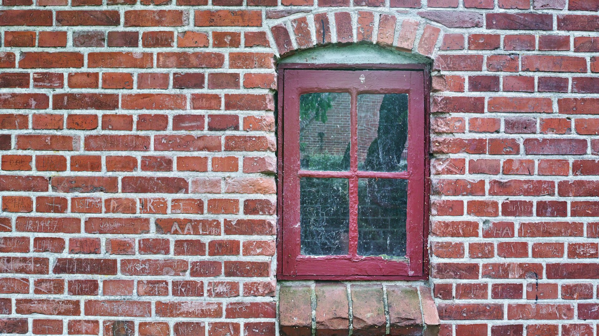roof-restoration An old, weathered, single-pane window in the middle of a red brick building in Central New York.