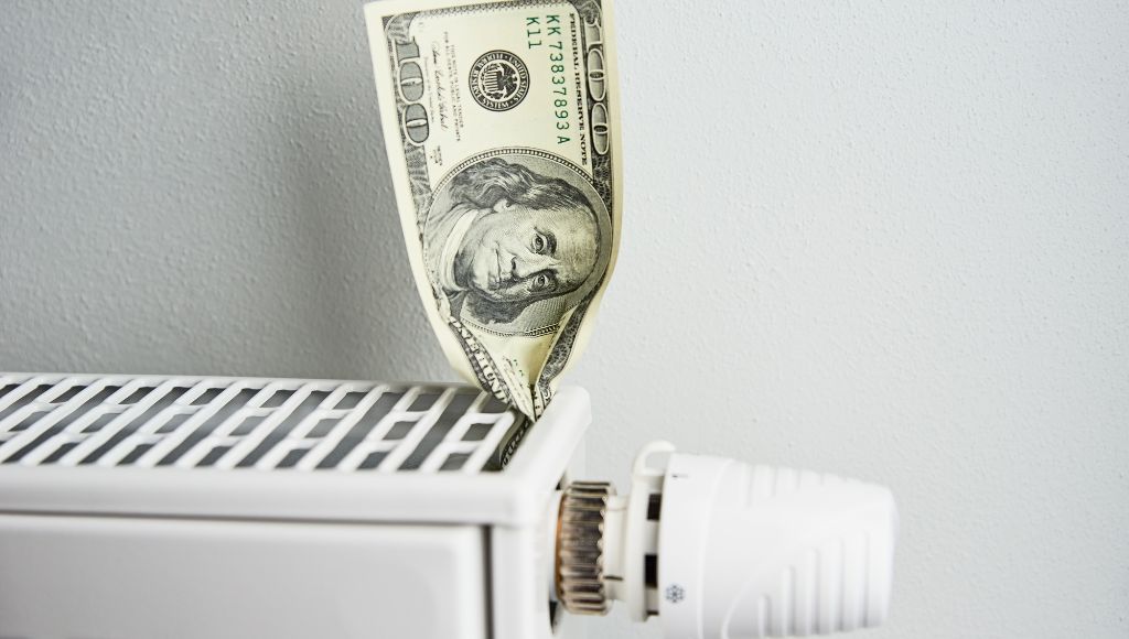 A close-up shot of a one-hundred-dollar US bill stuck in a white radiator.