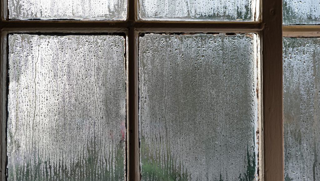 Condensation forming on the inside of a single-pane window.